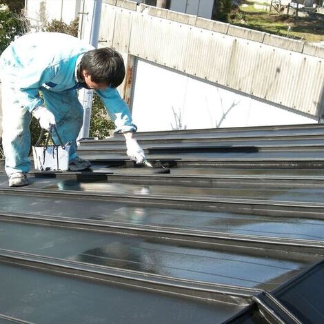屋根の塗装作業を進める職人